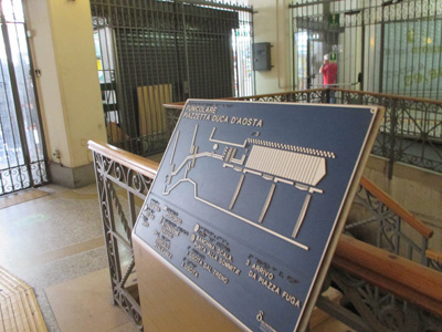 Photo shows steps leading up to the map with a row of detectable warning (truncated domes) along the top step, and raised bars leading from there to the map and out the exit.  The bars have a different texture in front of the map.